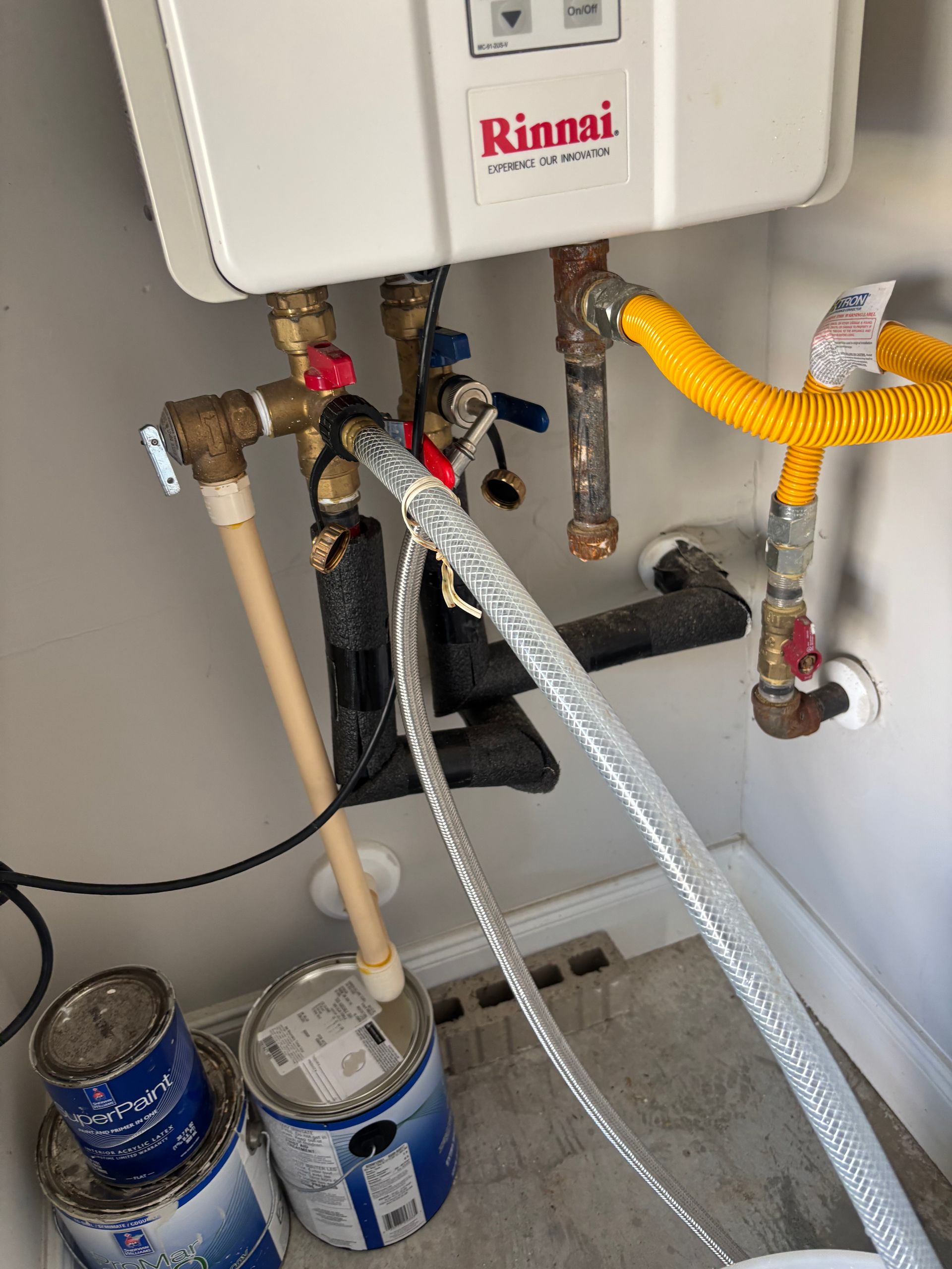 Plumber tightening a pipe fitting with a wrench beside a pressure gauge and copper pipes