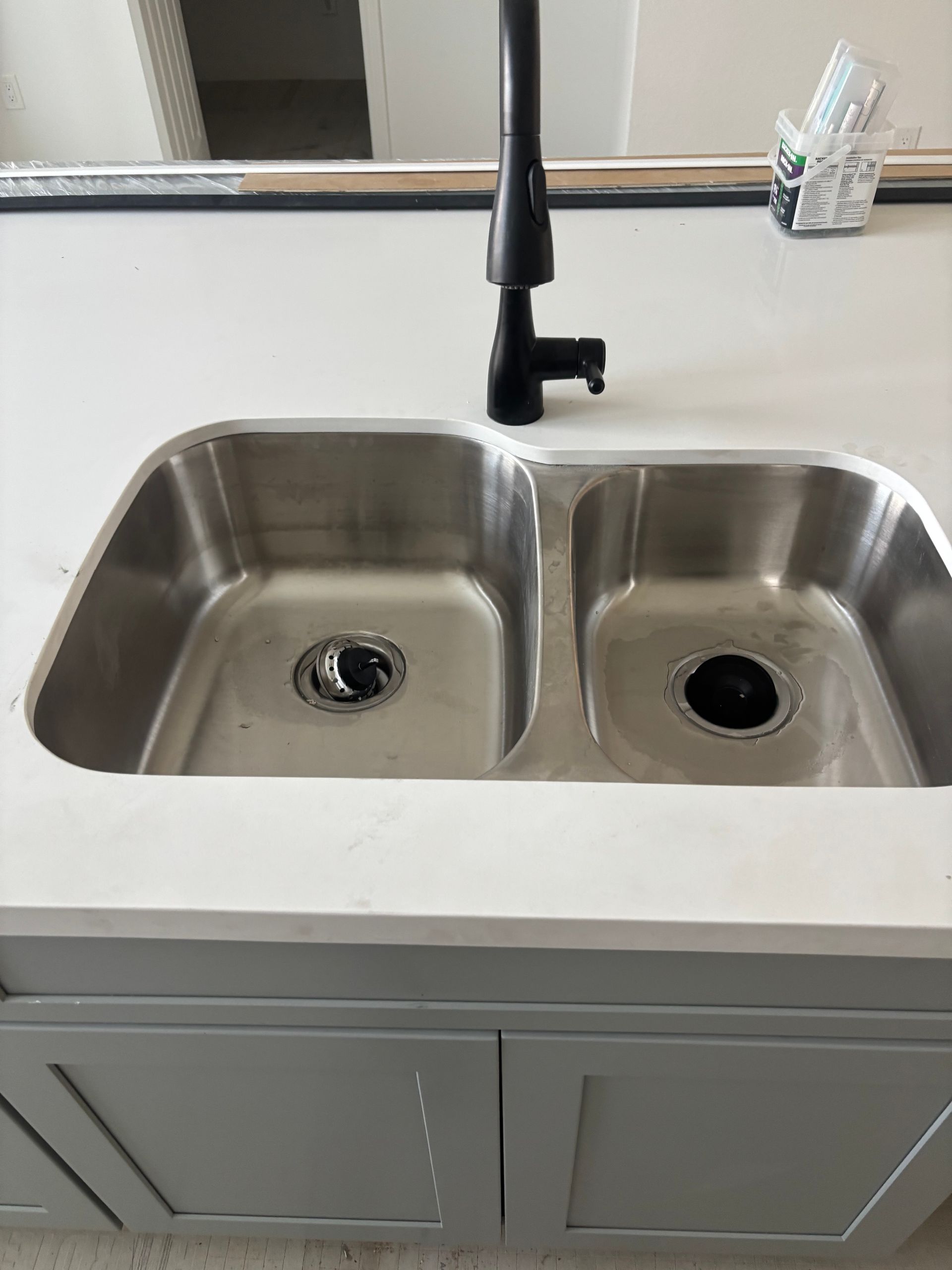 Plumber in blue uniform repairing a kitchen sink faucet with tools on the counter