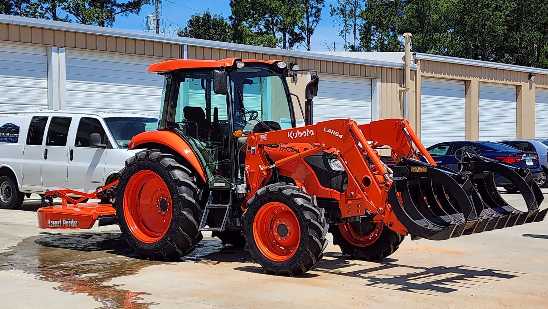 Orange Kubota tractor with front loader parked outdoors.