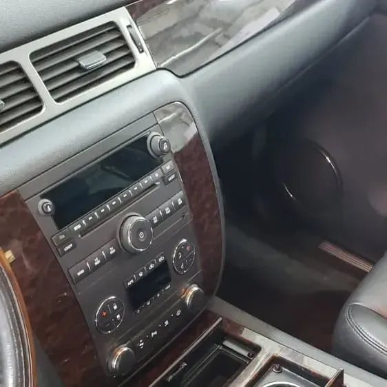 Car's interior: dashboard with radio, air vents, wood trim, and cup holder.