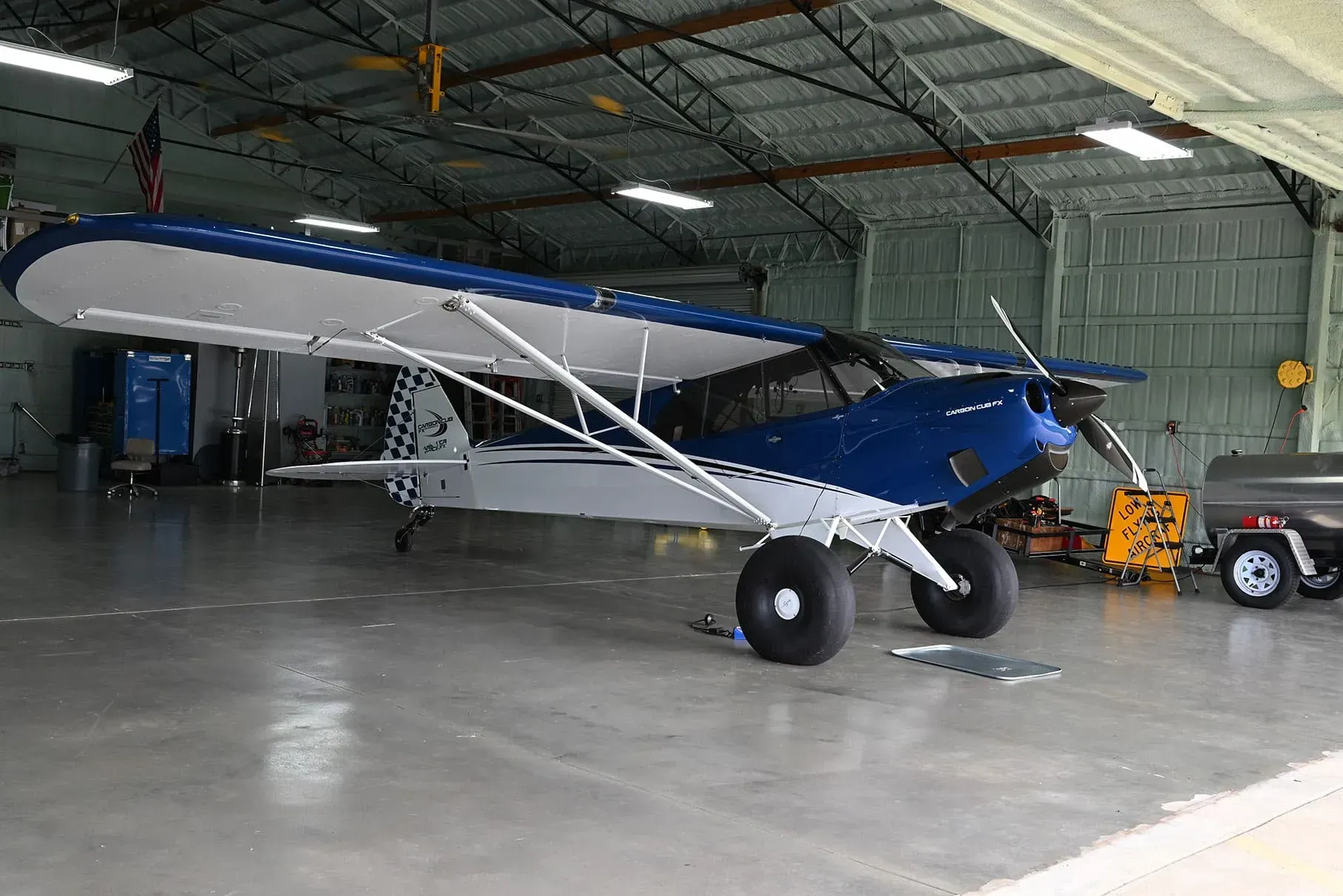 Blue and white airplane in a hangar, parked on a concrete floor.