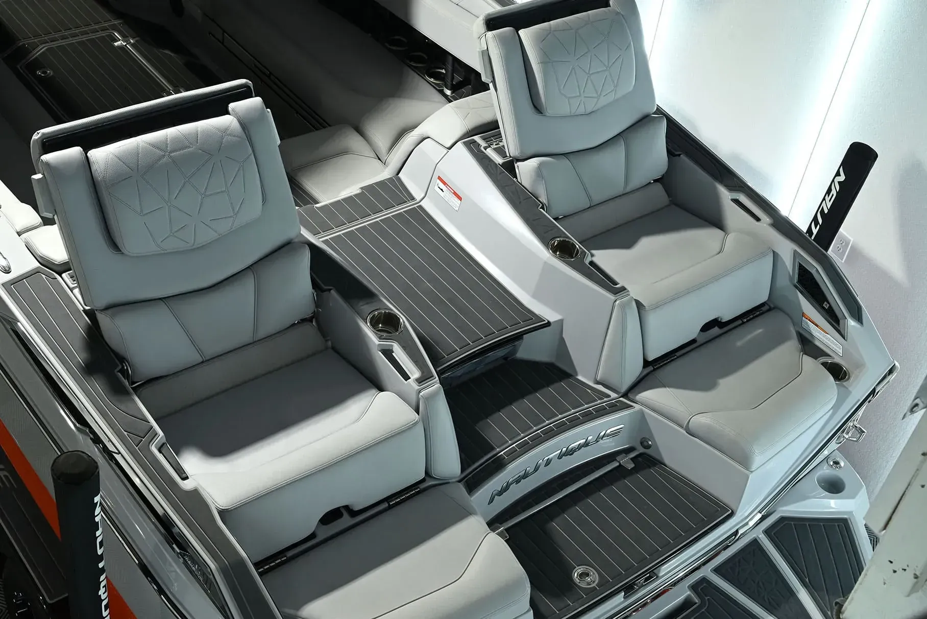 Two gray boat seats with a table and cup holders on a boat deck.