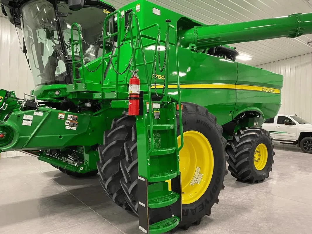 Green John Deere combine with a ladder and a fire extinguisher, indoors.