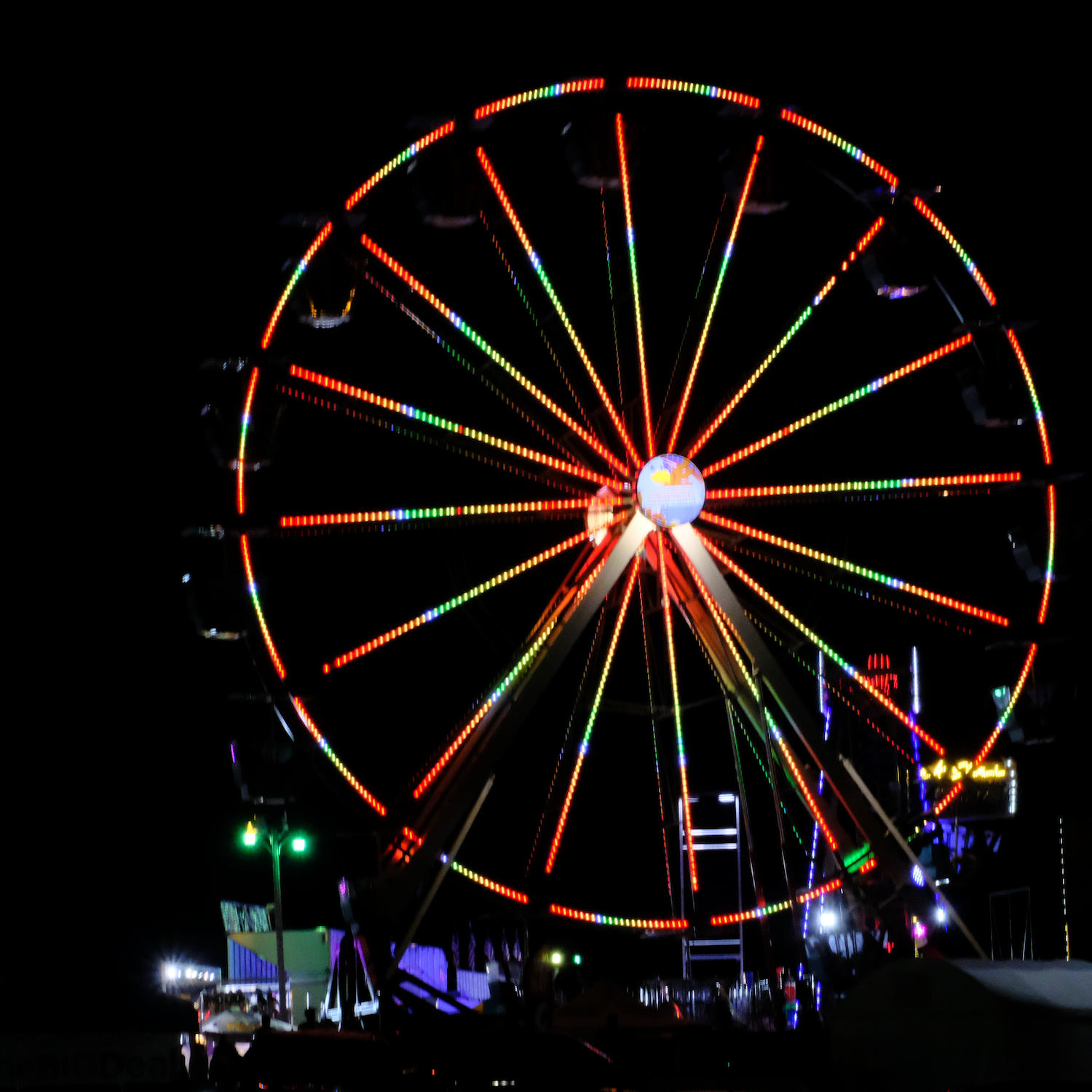Ferris wheel at night, illuminated with colorful lights, set against a dark sky.