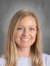 A woman in a white sweater is smiling for the camera.