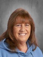 A woman in a blue hoodie is smiling for the camera.