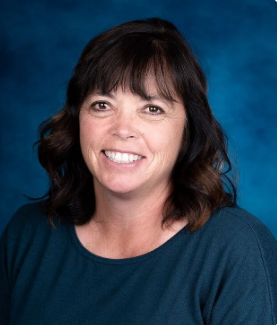 A woman in a light blue shirt is smiling for the camera