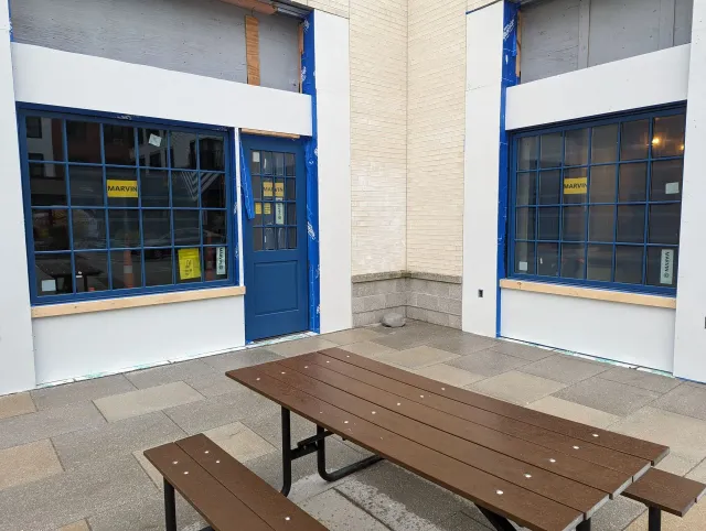 A picnic table in front of a building with a blue door