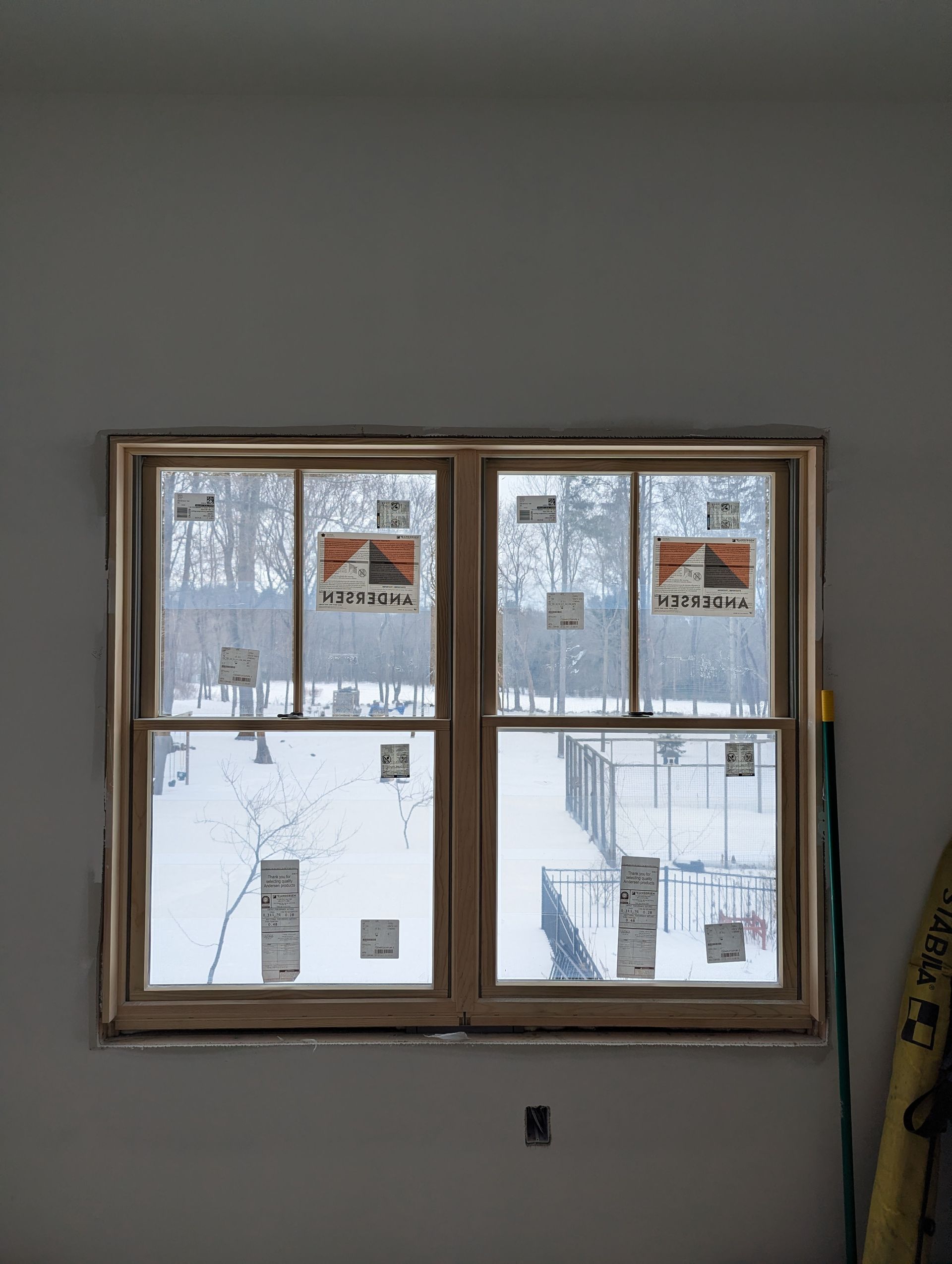Wooden-framed window with snowy buildings visible outside in a gray interior room