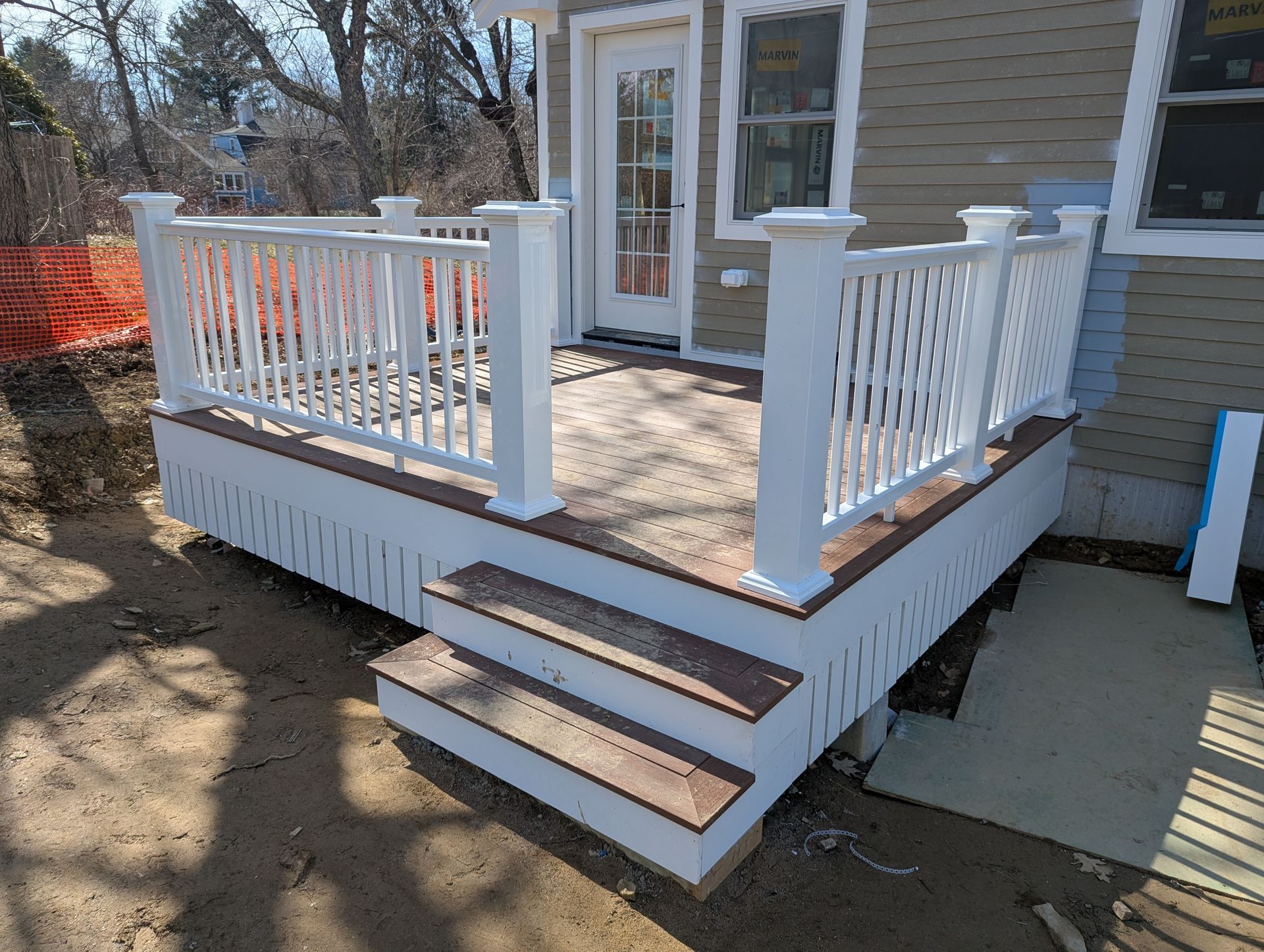 Back porch with white railings, tan siding, and three wooden steps leading to a door