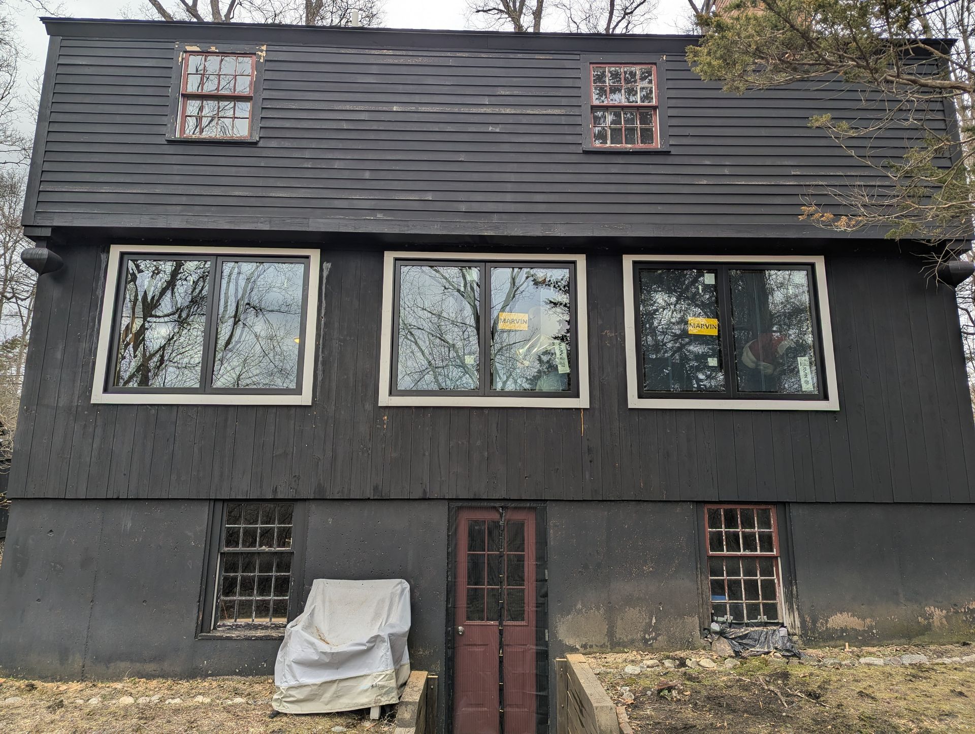 Dark gray two-story house with large windows and a red front door