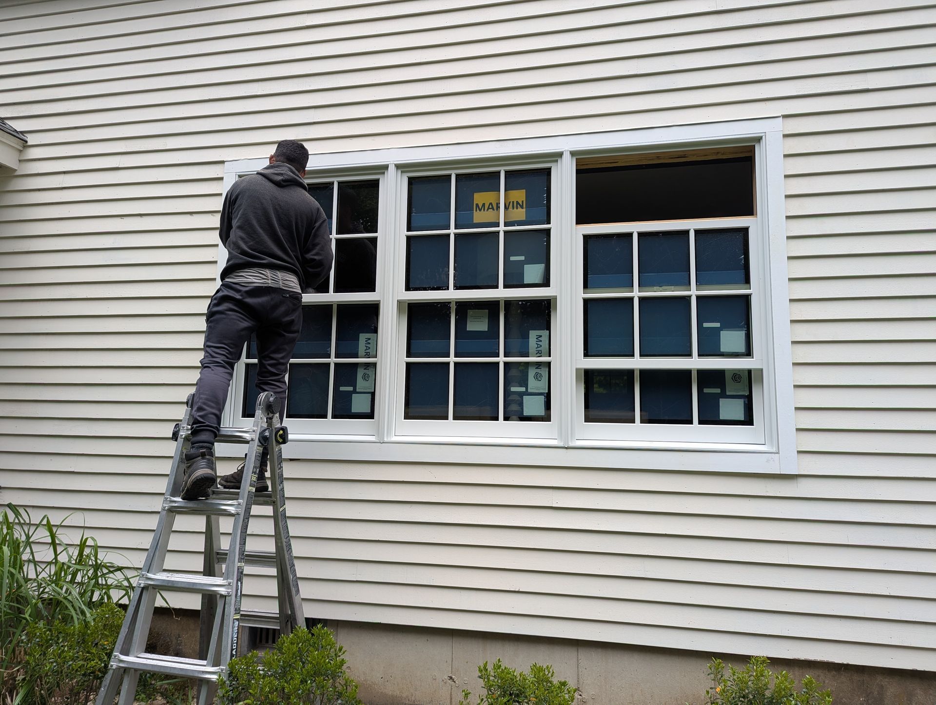 Person on ladder cleaning a house window from the outside