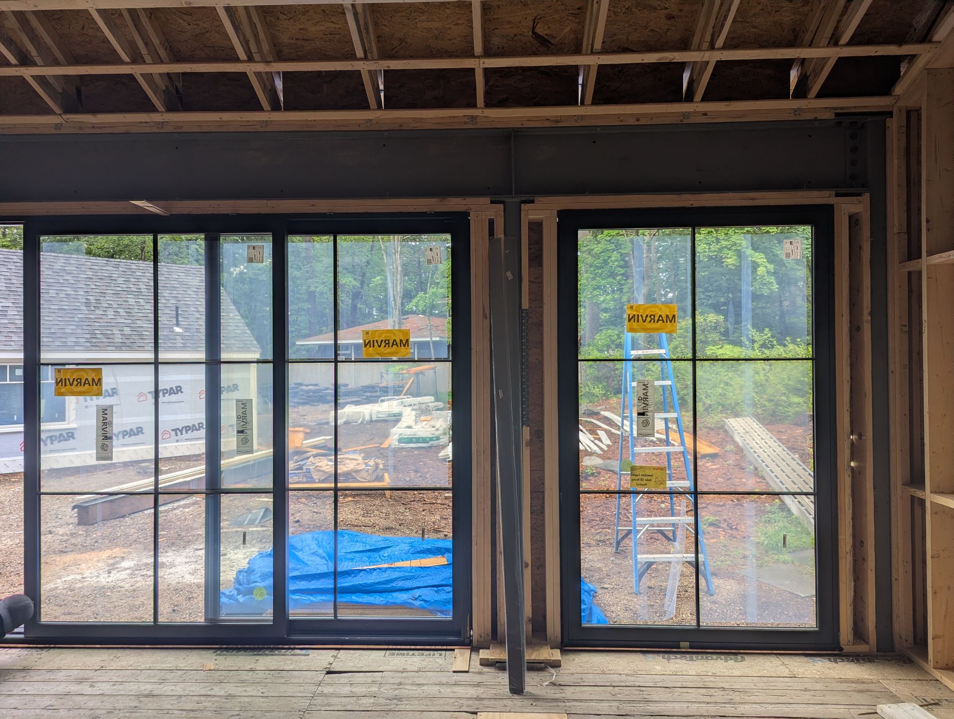 Interior room with large glass doors and windows, showing a construction site outside.
