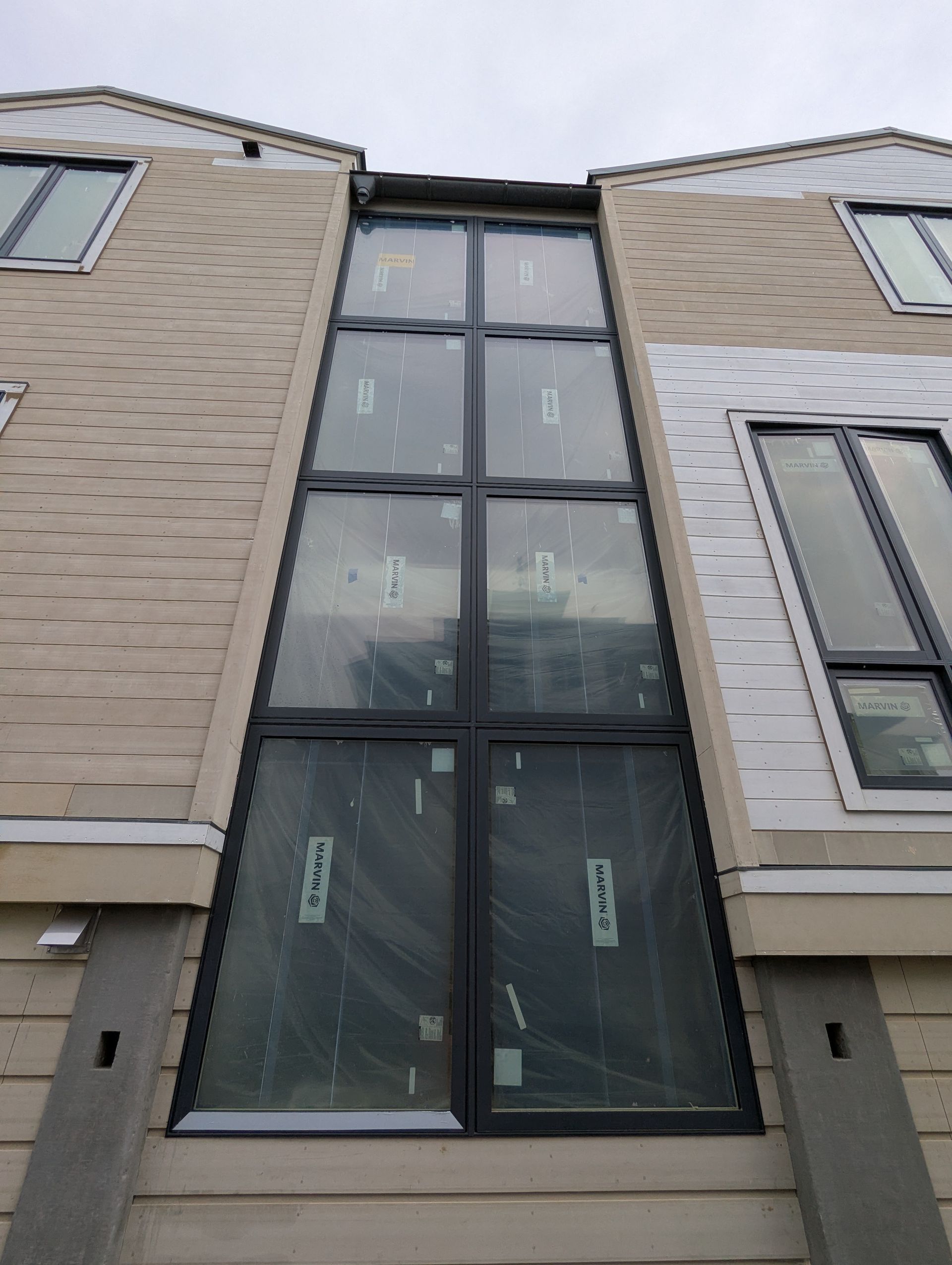 Tall narrow black-framed window on a beige brick building facade