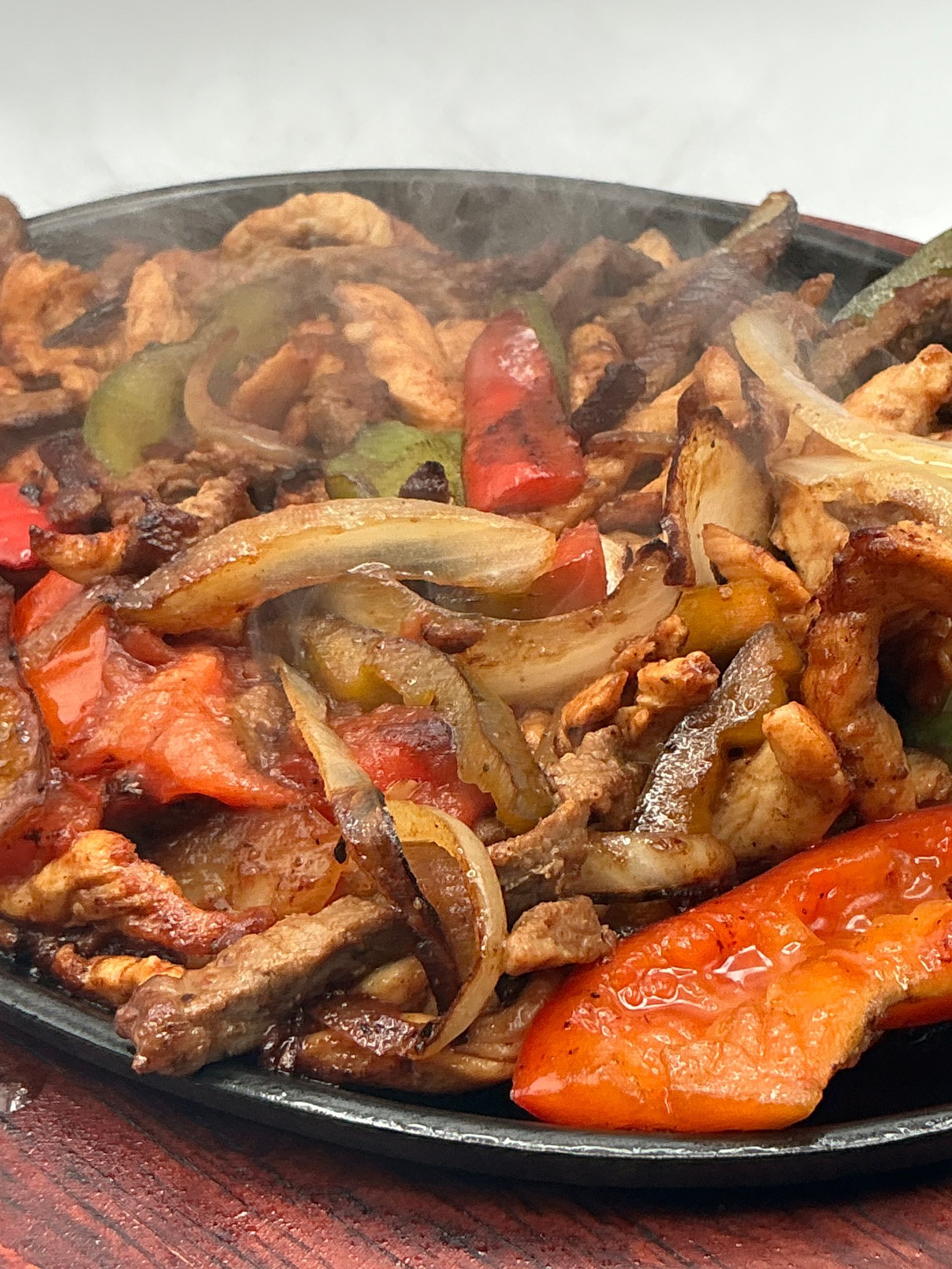 Sizzling chicken fajitas with onions and bell peppers on a hot skillet.