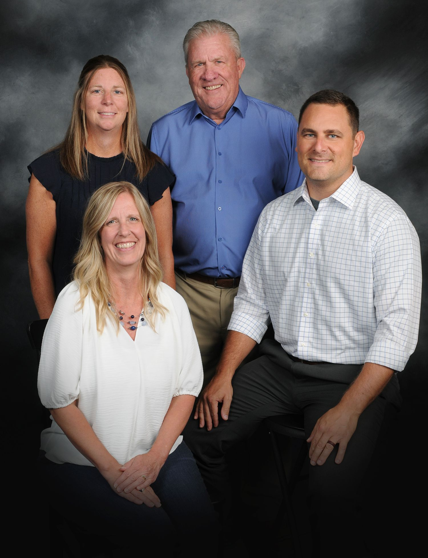 Four people posing for a studio portrait against a gray backdrop
