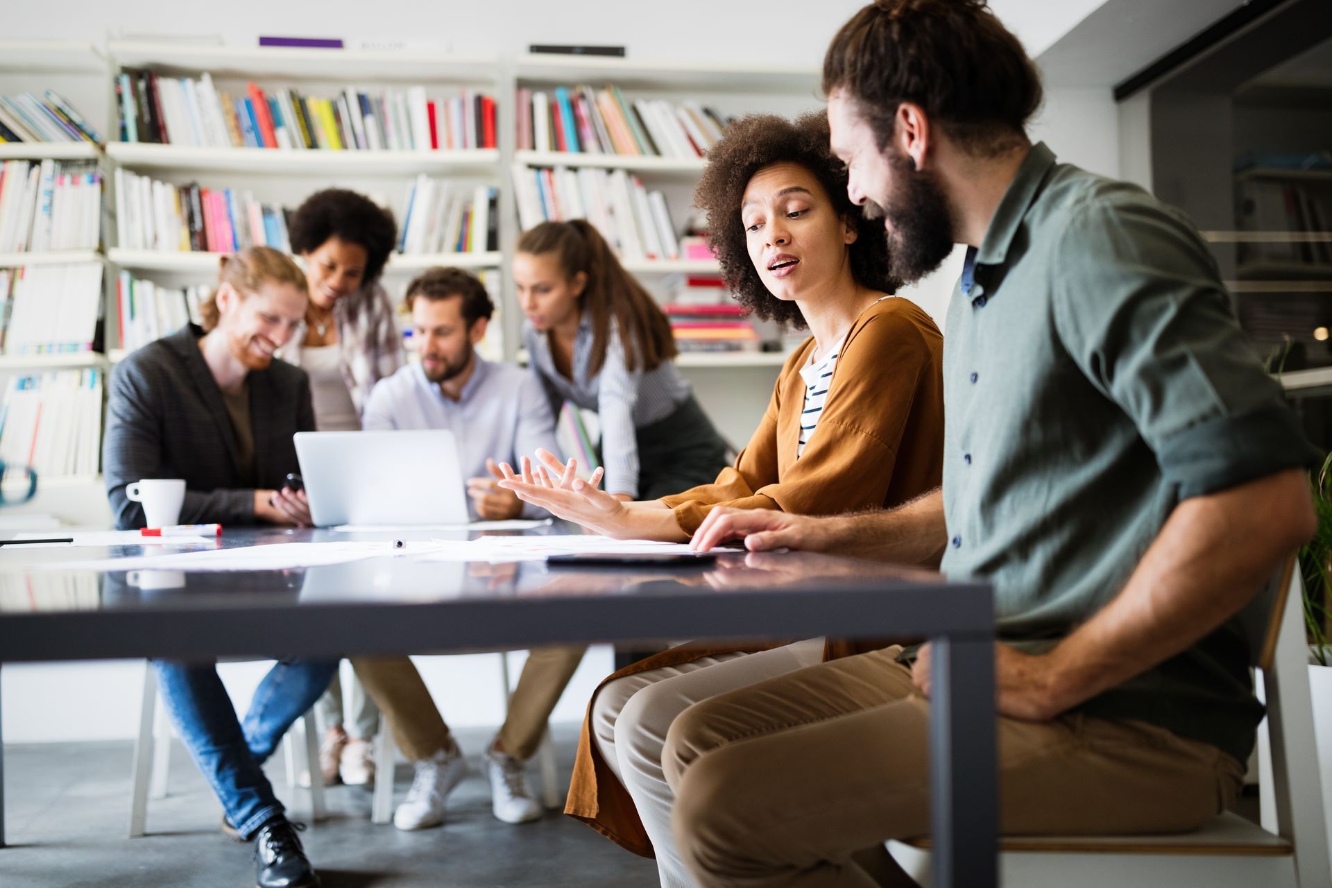 Team collaborating around a laptop at a conference table in a bright office.