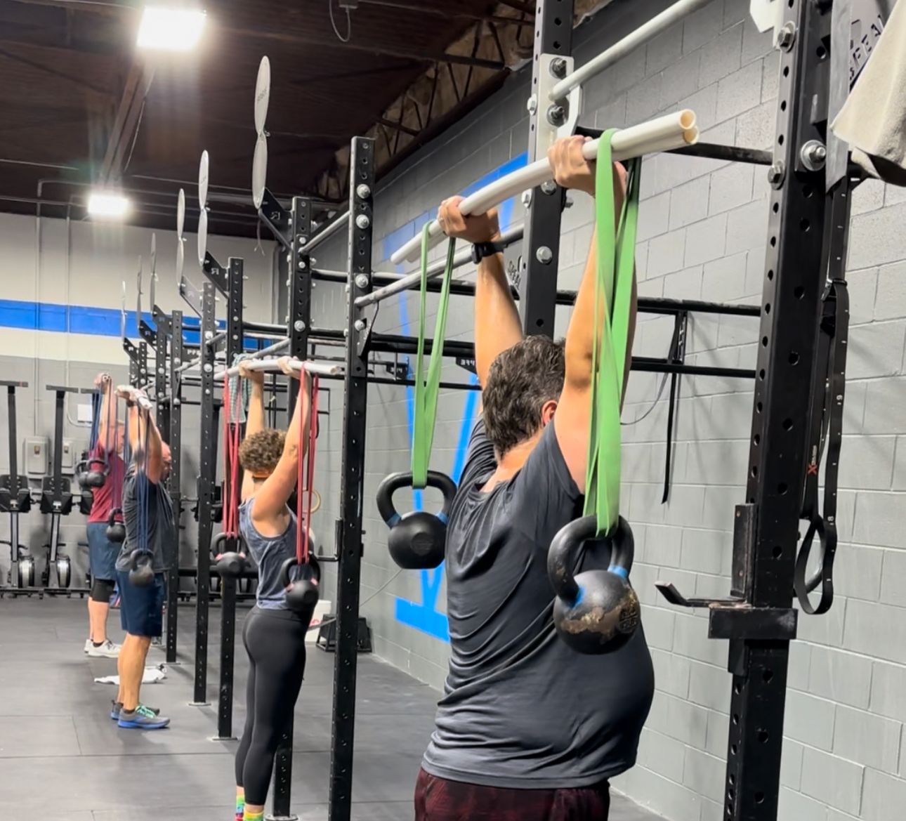 A group of people are doing pull ups in a gym.
