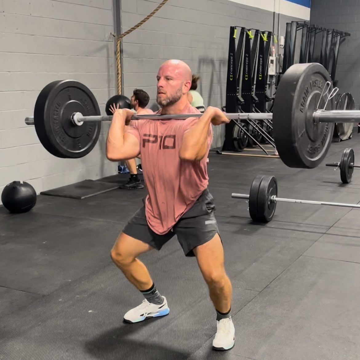 A man lifting a barbell in a gym with the word pio on his shirt