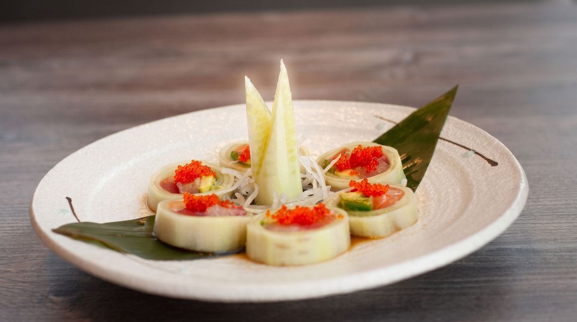 Plated seafood appetizer with red garnish and lettuce on a white dish