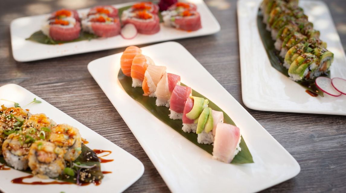 Assorted sushi rolls and nigiri arranged on white platters on a table.