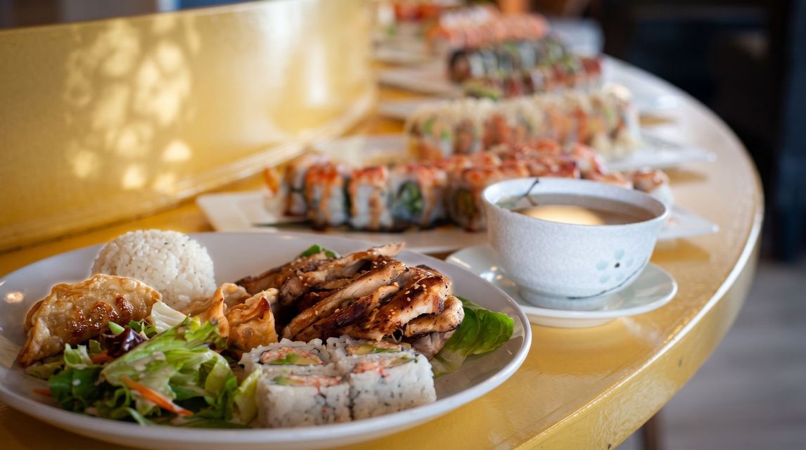 Plates of sushi and a bowl of soup on a curved table at a restaurant.