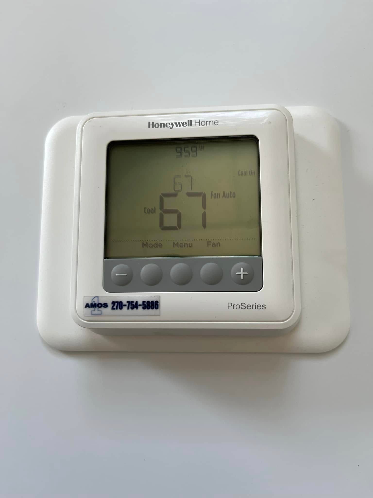 White wall thermostat displaying 67°F with gray buttons and digital screen