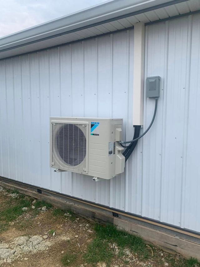 Wall-mounted outdoor air conditioner unit on the side of a white building