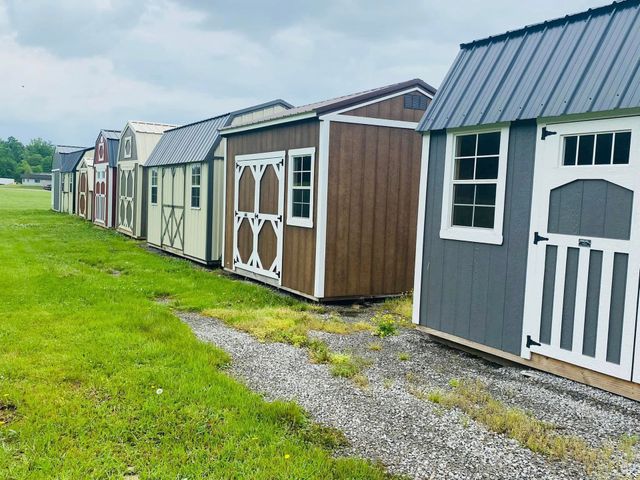 Row of colorful small sheds on a grassy lot under a cloudy sky