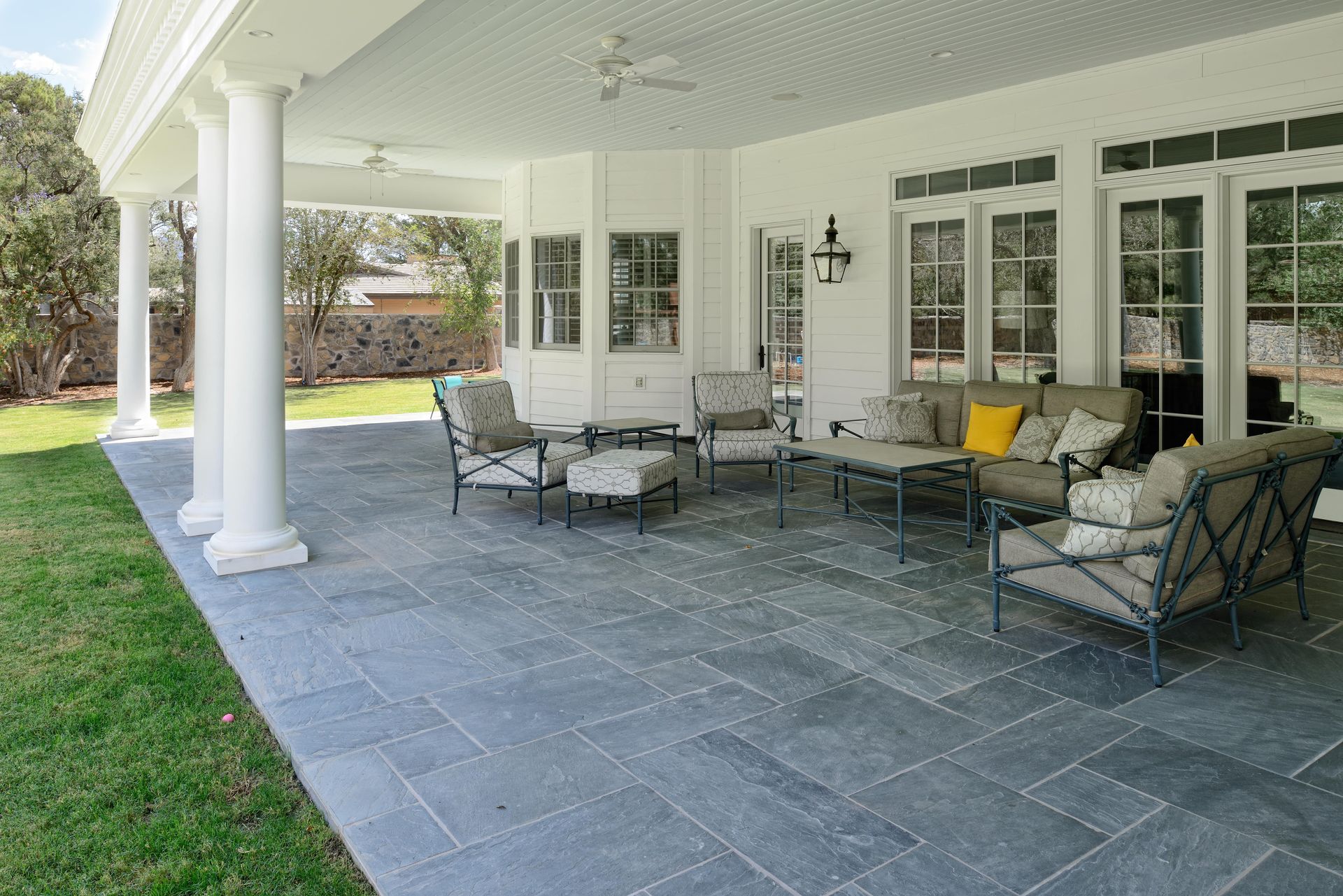 Covered patio with blue stone flooring and outdoor seating.