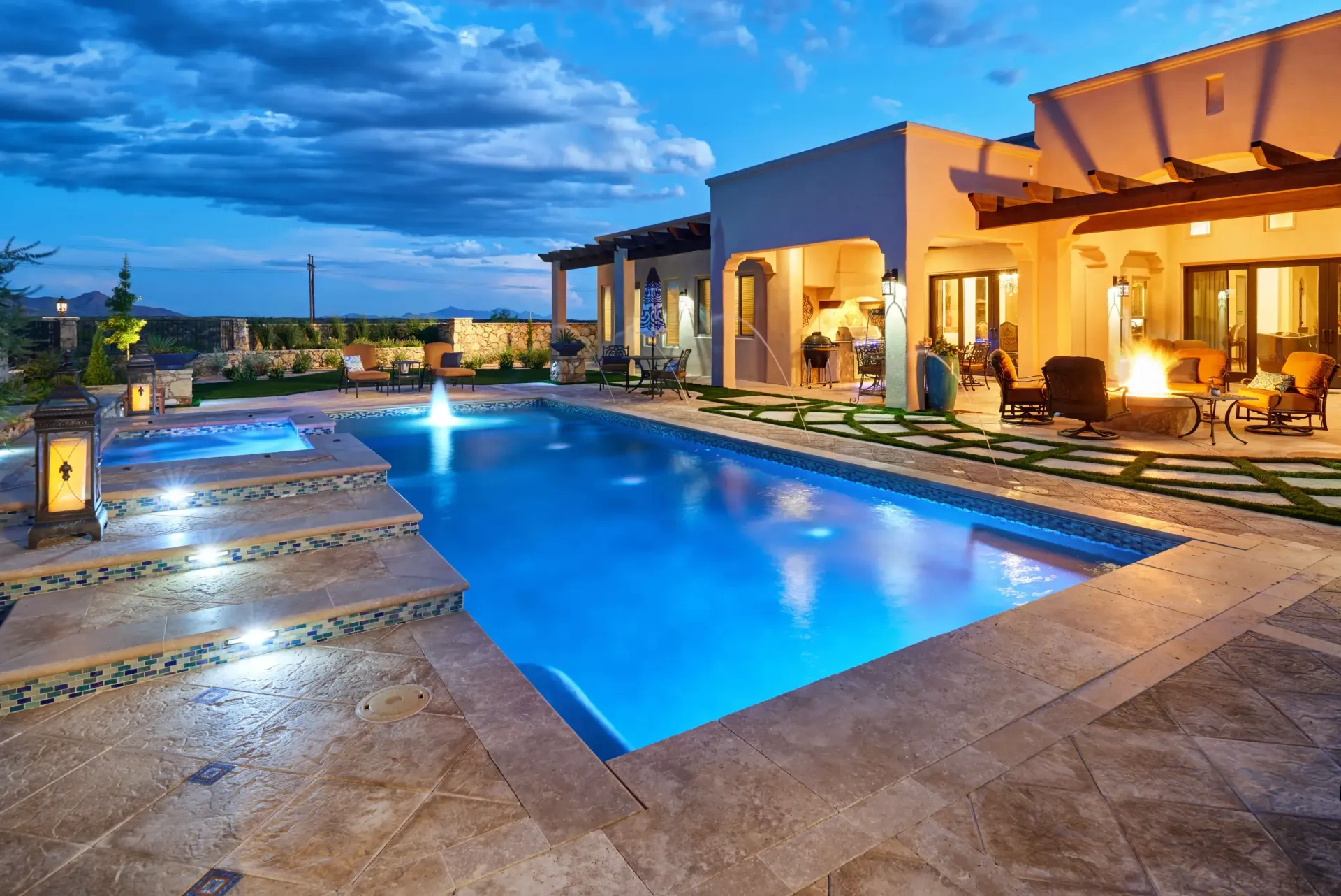 Night view of a luxurious swimming pool with illuminated steps and a lit-up house patio.