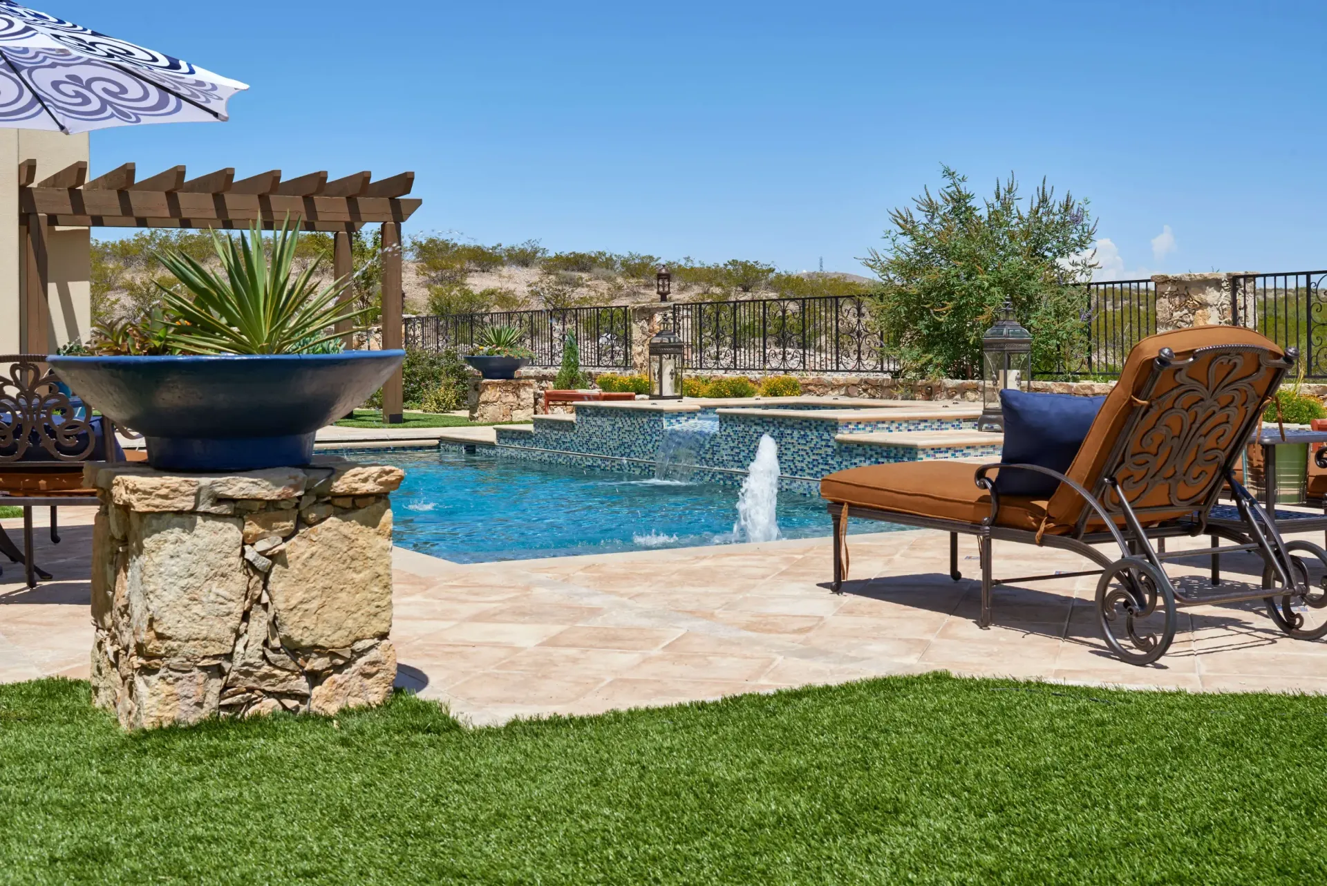 Swimming pool with fountain and lounge chair on a sunny day.