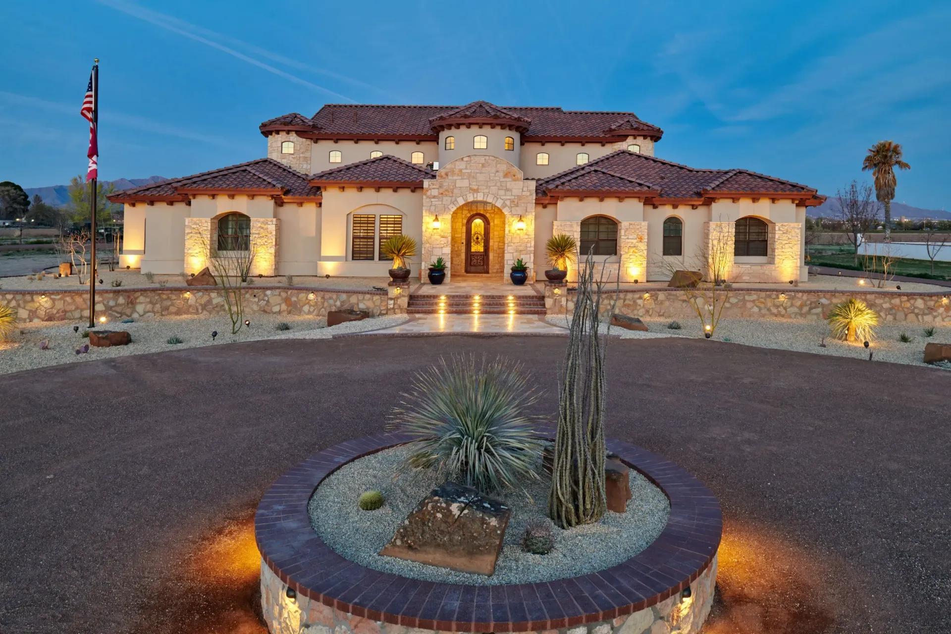 Luxury home with illuminated facade and circular drive.
