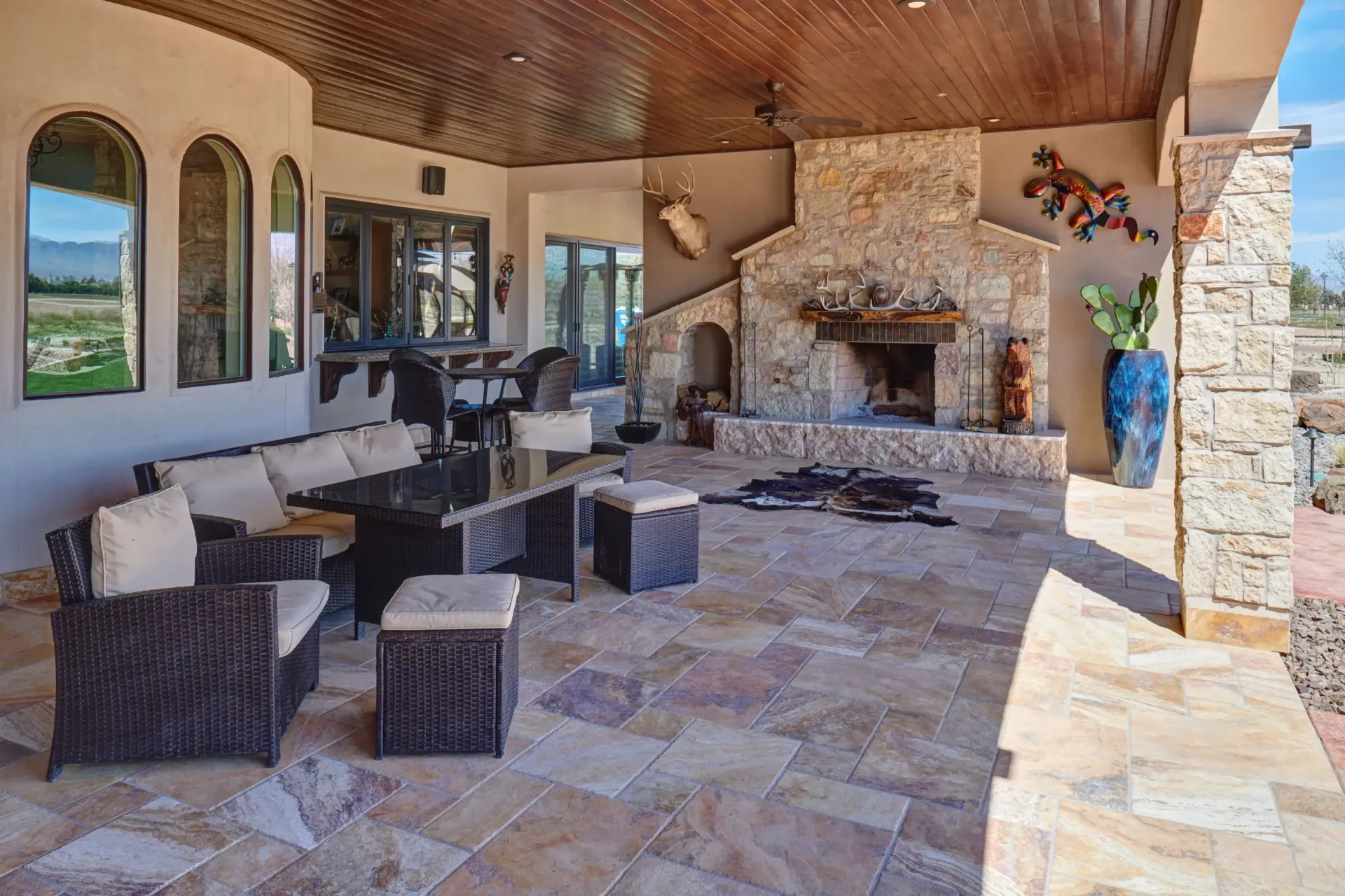 Outdoor patio with seating, fireplace, and stone flooring.