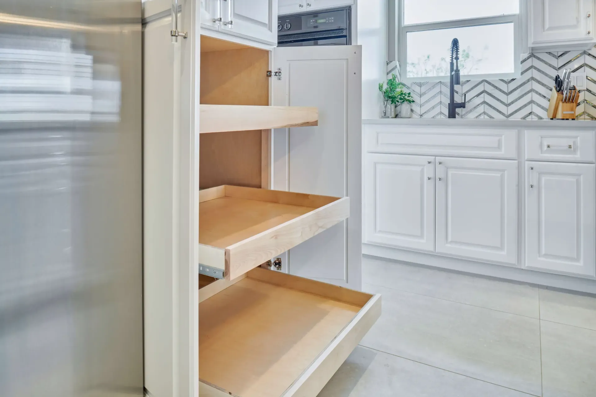 White kitchen pantry cabinet with pull-out shelves, open showing the interior.