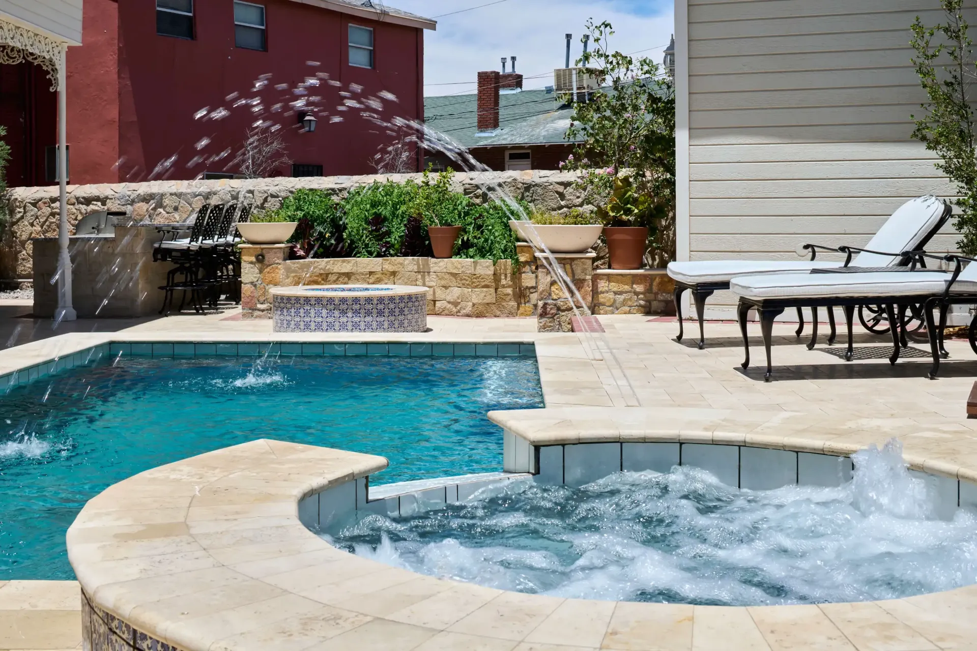 Outdoor swimming pool with jacuzzi, fountains, and patio furniture.