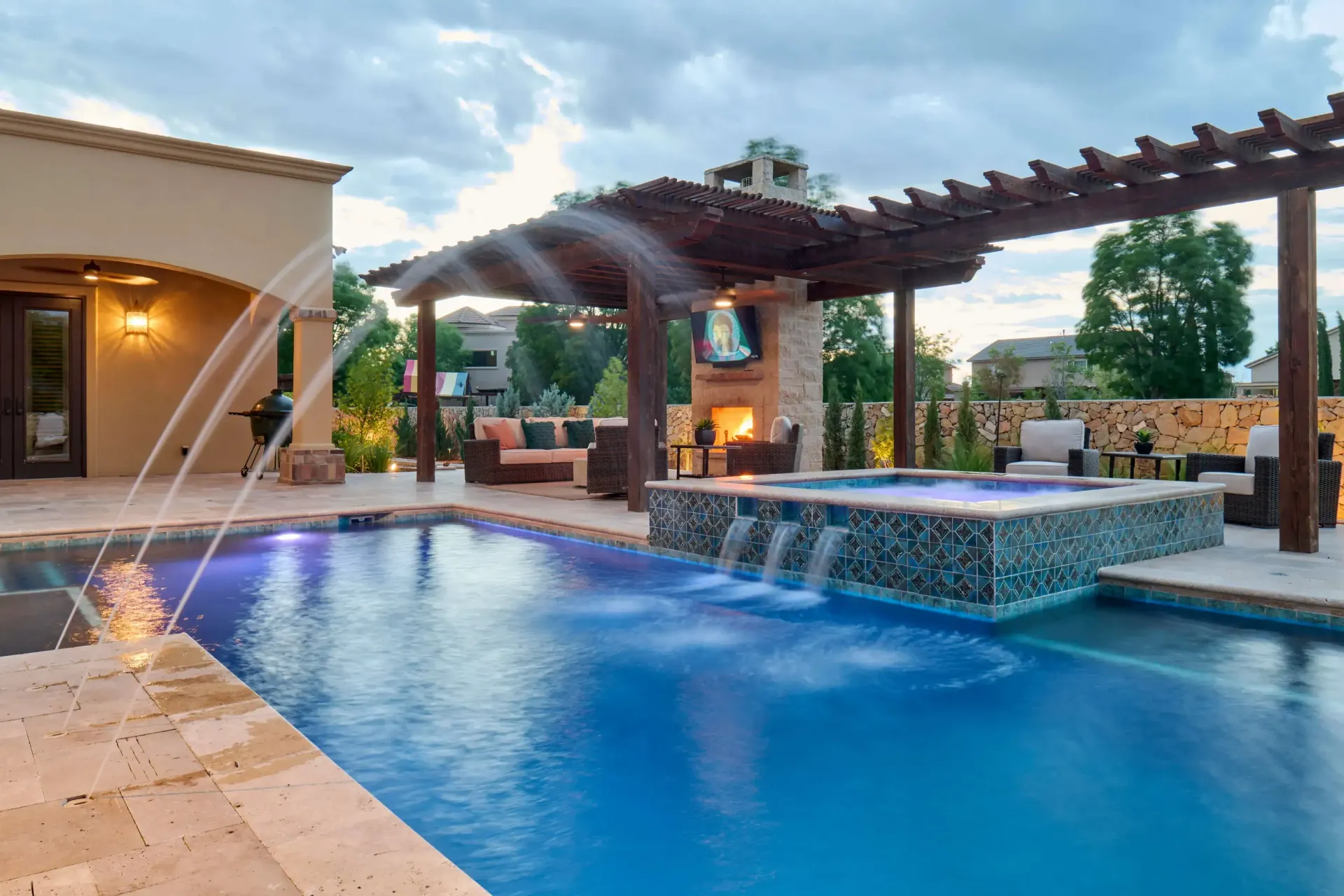 Poolside lounge area with a pool, hot tub, fireplace, and pergola.