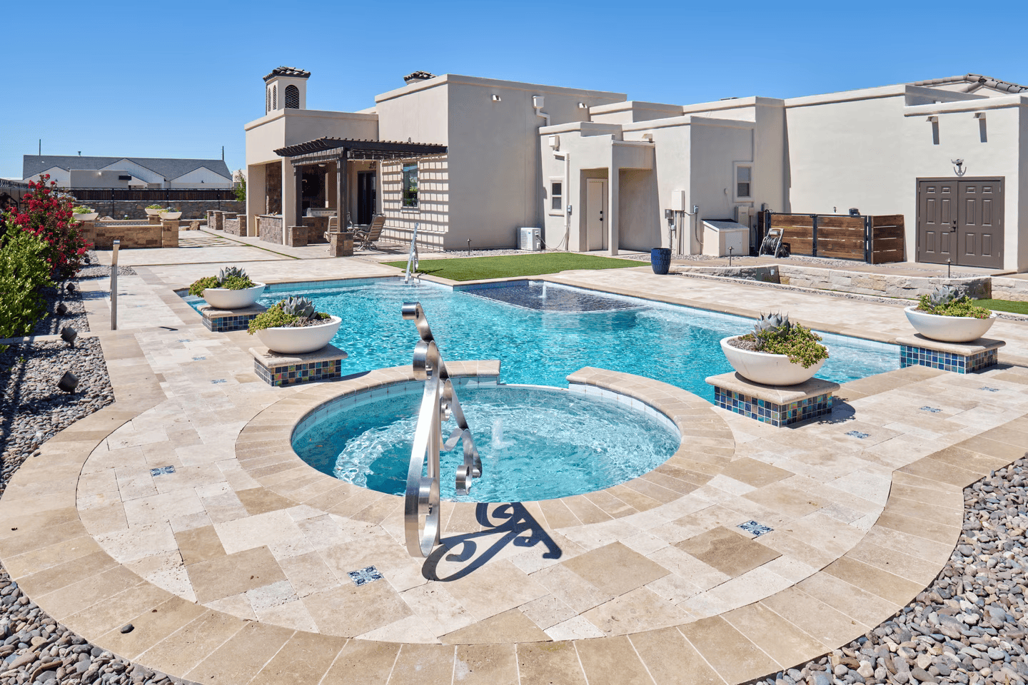 Swimming pool and hot tub in a backyard of a tan stucco home.