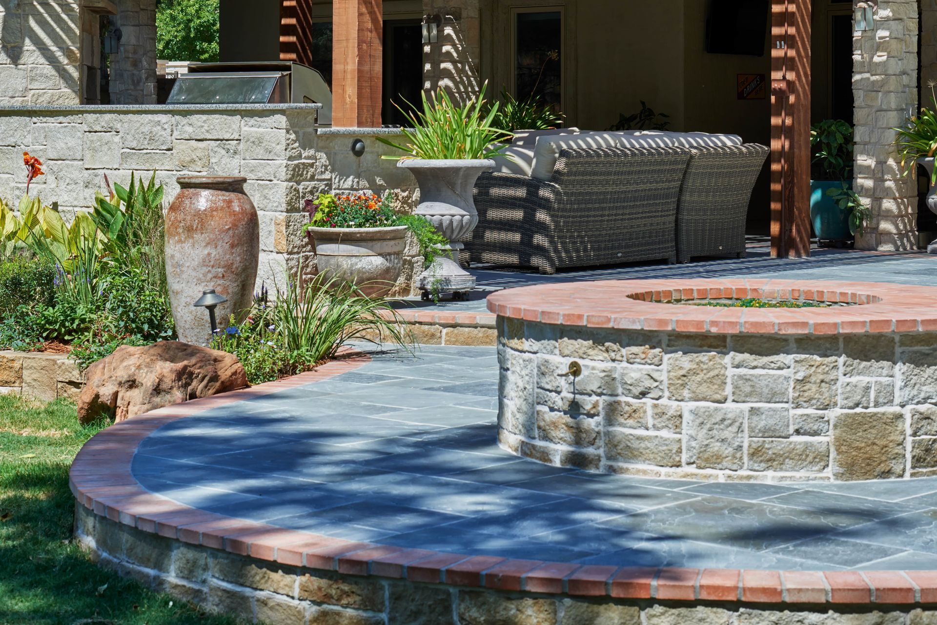 Outdoor patio with fire pit and seating area, surrounded by landscaping.