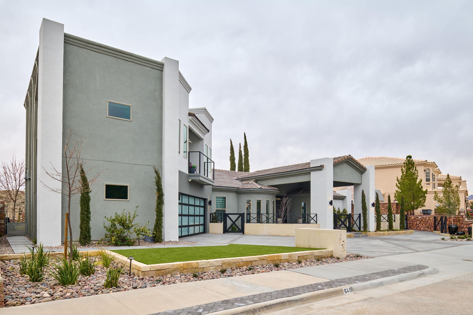 Modern gray house with white trim, glass garage door, and small front yard.