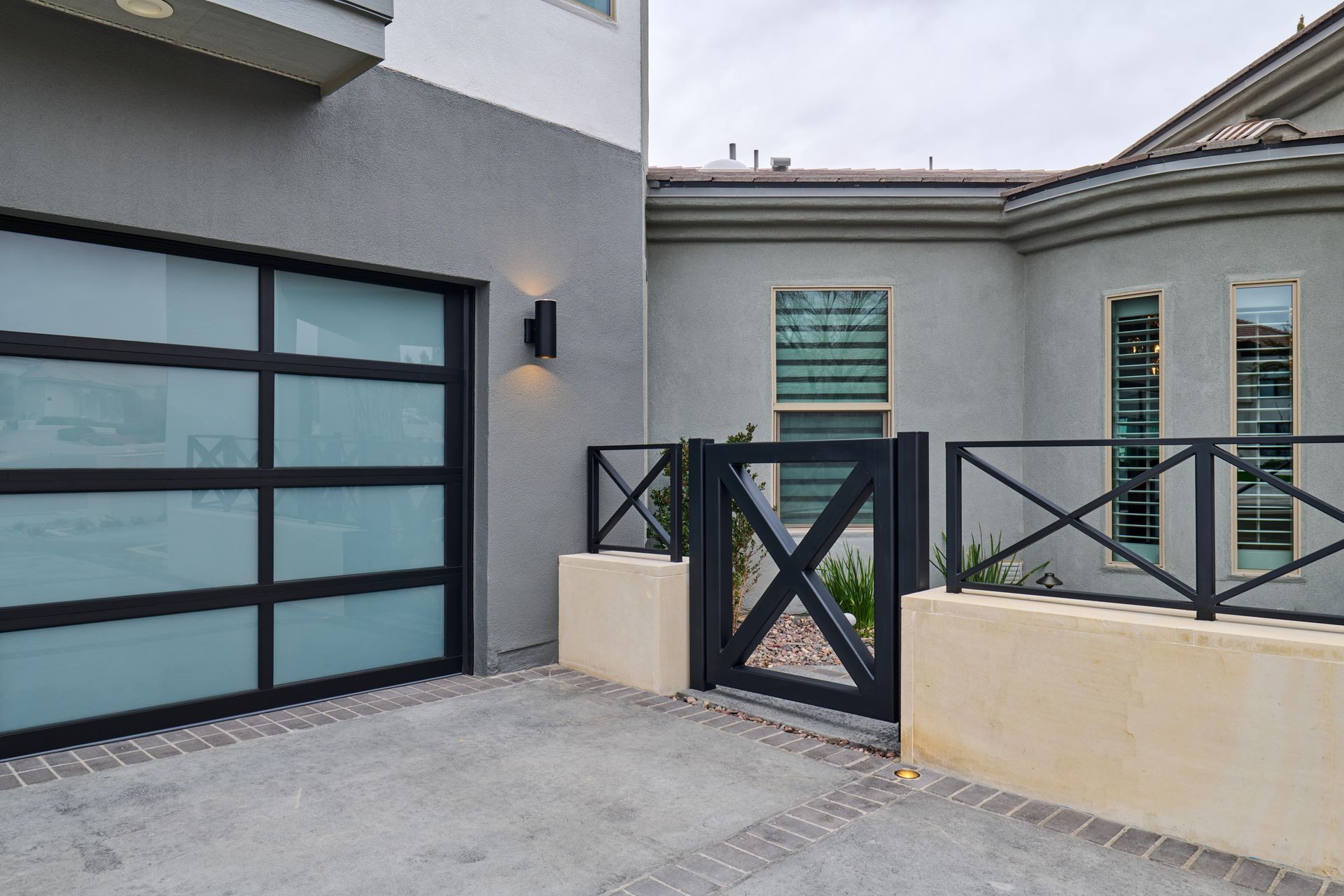 Modern house exterior with black garage door, gate, and light-colored walls.