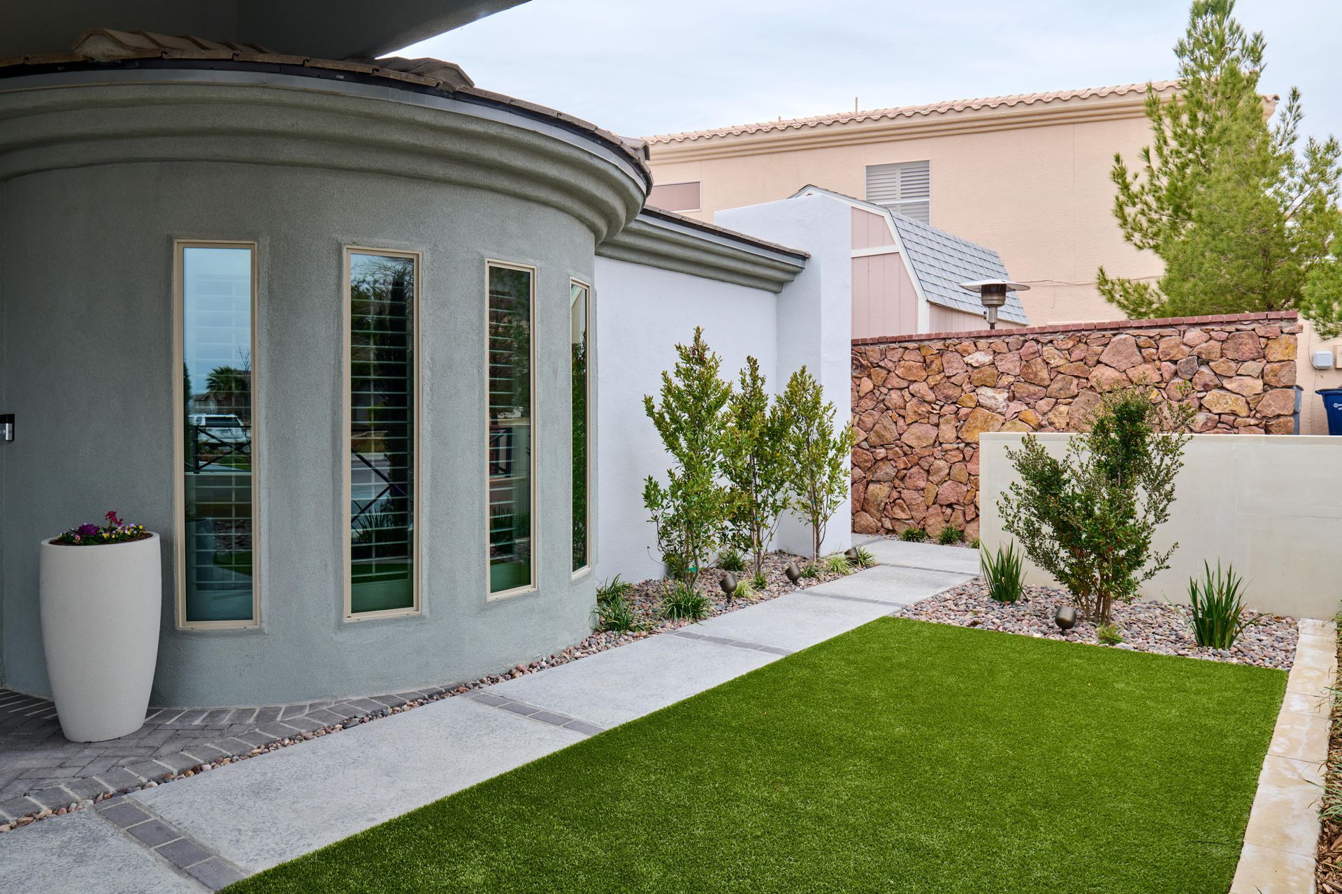 Exterior of a modern house with a green lawn and a stone wall.