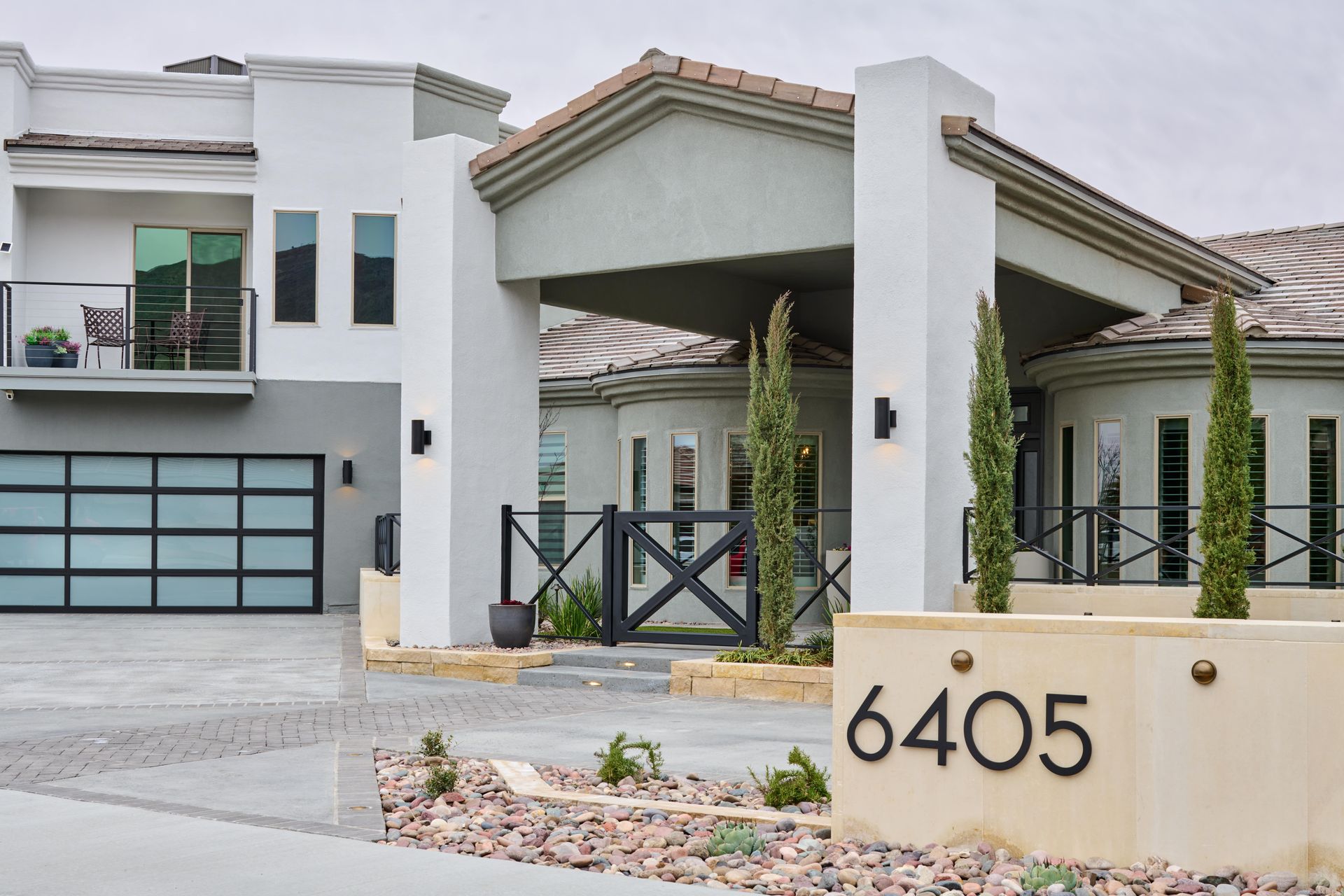 Modern home exterior with address 6405, gray facade, glass garage door, and landscaping.