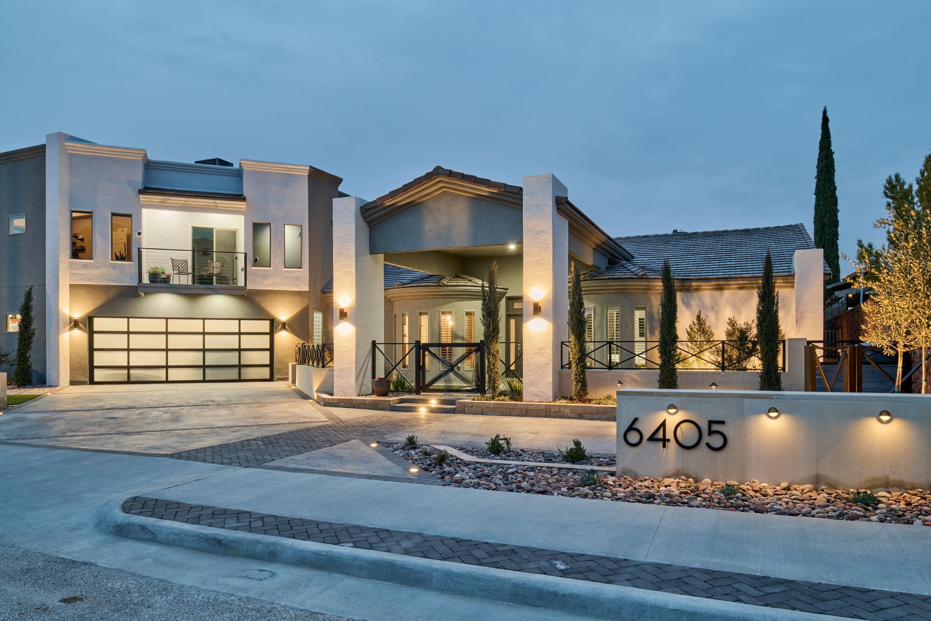 Modern home with multi-level architecture, illuminated at dusk, street view.