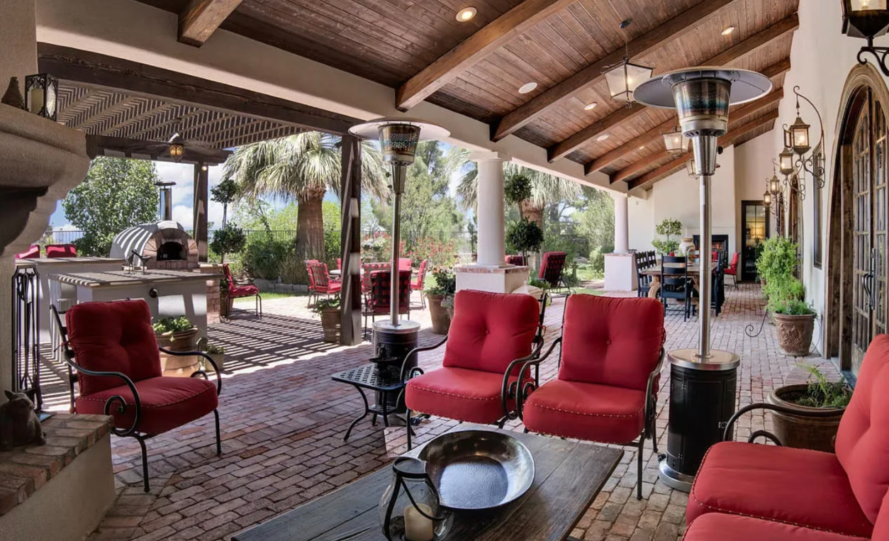 Outdoor patio with red seating, brick floor, and overhead beams.