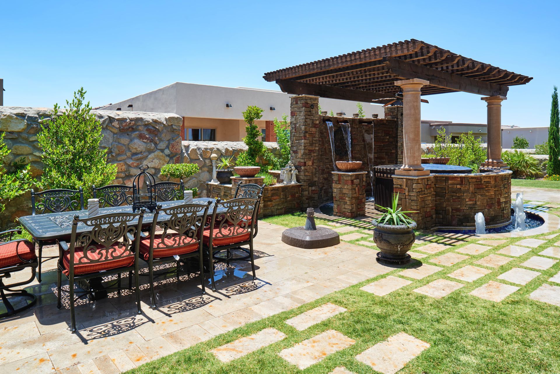 Outdoor patio with dining table and water feature with pergola.