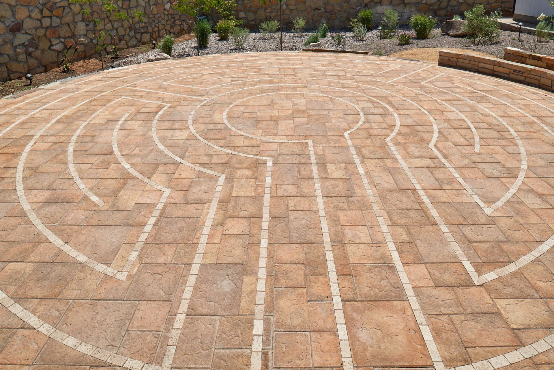 Stone labyrinth with curved paths, set outdoors on a sunny day.