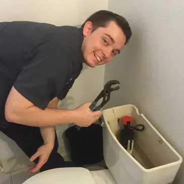 A man is fixing a toilet with a wrench
