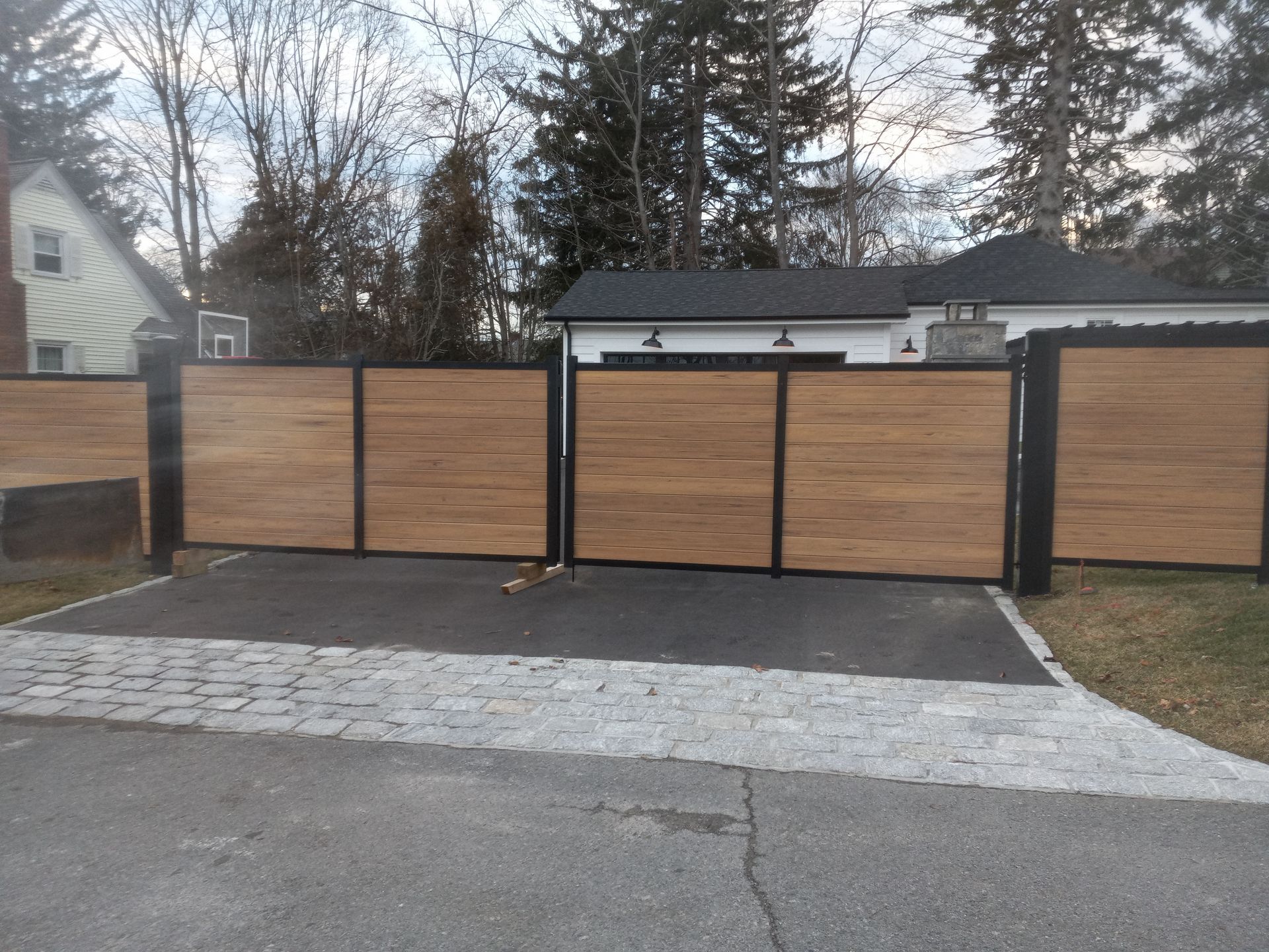 Wooden driveway gates with black metal frames.