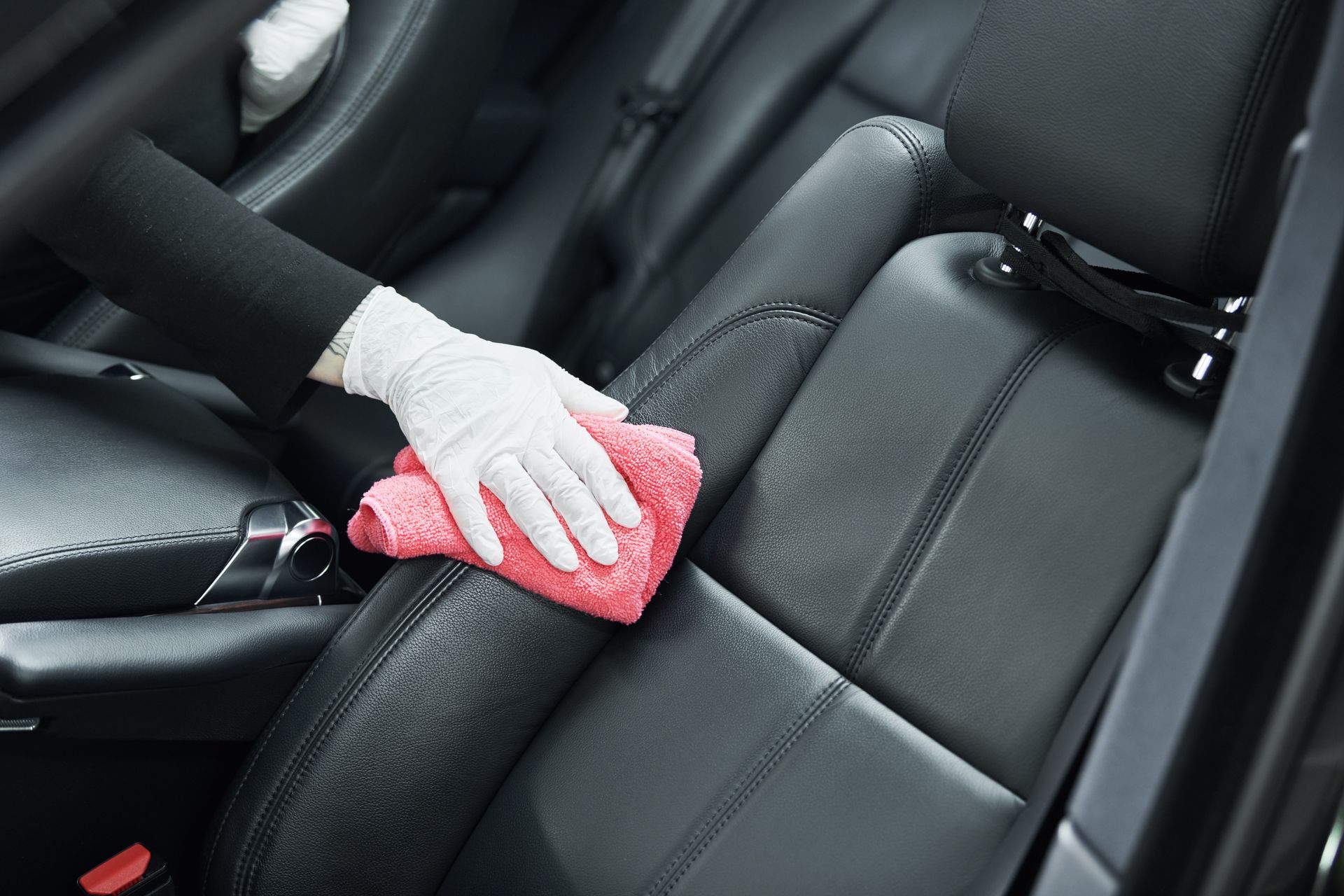 A person is cleaning the seats of a car with a cloth.